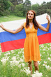 © Ekaterina - Young woman in a yellow dress with the national flag of Russia outdoors in a flowering field.
