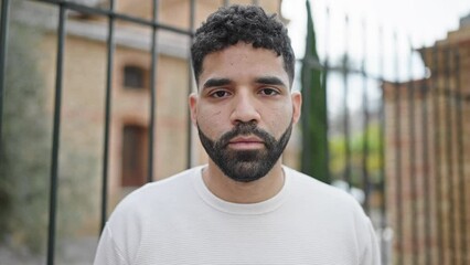 Sticker - Young hispanic man standing with serious expression at street