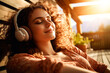 © Haydiddle - Pretty young woman laying down and relaxing while listening to music on headphones with a smile on her face.