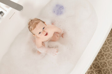 Sticker - Cute little baby bathing in tub at home, top view