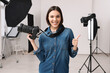 Professional photographer with camera showing thumbs up in modern photo studio