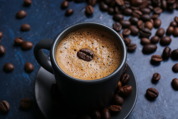 Cup of hot espresso and coffee beans on blue background