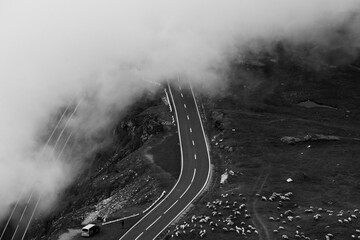 Poster - Grayscale of the majestic fog-covered green mountains and winding Transfagarasan road