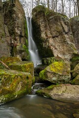 Sticker - Tranquil landscape featuring a lush green forest with a majestic waterfall cascading over the rocks