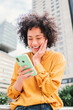 © Jose Calsina - Vertical portrait of young adult woman using a cellphone surprised by good sales. Female watching shocked the screen of the smart phone. Excited, happy and amazed girl with victory face expression