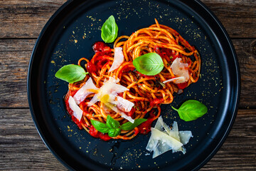 Spaghetti marinara with parmesan cheese and basil leaves served on wooden table
