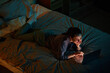 © Seventyfour - Portrait of young woman watching movies at night while lying on bed