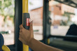 Woman's hand operating the bus stop request button. Close up image of a young girl's hand pressing a stop button for the bus to stop and she can get off at her selected stop.