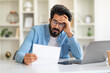 © Prostock-studio - Upset Young Indian Man Sitting At Desk With Laptop And Checking Documents