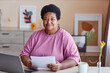 © Seventyfour - Aged African American businesswoman in casual attire looking at camera while sitting by desk in front of laptop and working at home office