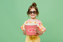 Young Smiling Cheerful Satisfied Happy Child Kid Girl 6-7 Years Old In 3d Glasses Watch Movie Film Hold Bucket Of Popcorn In Cinema Looking Camera Isolated On Plain Green Background Studio Portrait.