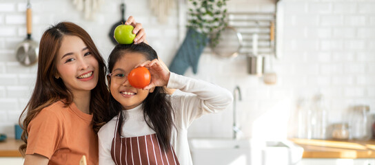 Portrait of enjoy happy love asian family mother and little asian girl daughter child having fun help cooking food healthy eat together with fresh vegetable salad and ingredient in kitchen