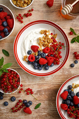 Poster - Yogurt with berries on wooden background. White plain greek yogurt with fresh berries and granola, top view. Healthy food, breakfast menu