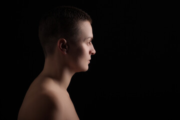 portrait of young woman with short hair and bare shoulder on black background