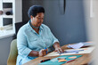 © Seventyfour - Serious mature craftswoman with scissors creating new composition on white sheet of paper while sitting by desk in studio of design and arts
