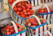 Baskets with fresh red strawberries for sale at farmers market in summer in France.