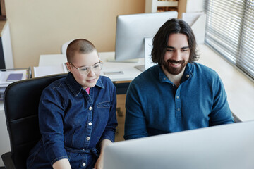 Two young professional IT engineers sitting in front of computer screen and watching online video describing basic points of cyber security