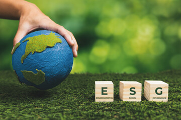 Businessman holding paper earth planet with ESG symbol wooden cube. Sustainable corporation development for environmental, social and governance idea to save the earth. Alter