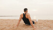 © Andrii Nekrasov - Middle-aged athletic man sits on the beach after workout and looks at the sea, Back view
