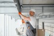 hvac services - worker install ducted pipe system for ventilation and air conditioning in office.