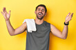 © Asier - Sporty Caucasian man with towel, studio shot on yellow Sporty Caucasian man with towel, studio shot on yellowreceiving a pleasant surprise, excited and raising hands.