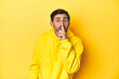 © Asier - Man in yellow hoodie, monochrome studio backdrop keeping a secret or asking for silence.