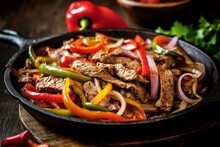 Delicious Home Cooked Beef Steak Fajitas In Iron Cast Skillet With Colorful Sweet Peppers And Onions. Traditional Mexican Specialty Popular Across America