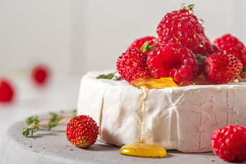 Wall Mural - Camembert cheese with fresh raspberries, strawberries, honey and thyme on white background. French appetizer