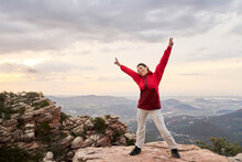 Carefree woman enjoying freedom in mountains during sunset