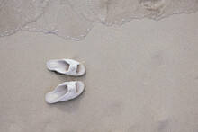 Top View Of Pair Of White Beach Slippers Near Sea