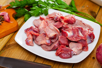 Wall Mural - Raw chicken gizzards served on plate on wooden table with herbs and garlic