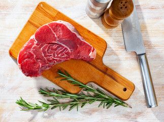 Wall Mural - Raw juicy veal steak with herbs ready for cooking on wooden table..