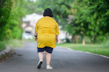 Wall Mural - back view fat asian girl exercising By walking to burn fat and jogging slowly, fat woman walks for exercise in a natural park.