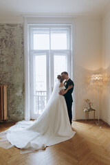 Wall Mural - The first meeting of the groom in a black suit and the bride in a white wedding dress with a bouquet in the interior of a photo studio on a white and black background