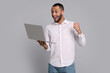 © New Africa - Happy young man with laptop on grey background. Space for text