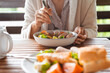 © Dulin - Woman eats a delicious and healthy breakfast with scrambled eggs, fresh salad, cheese, tomatoes and sausages. Healthy Breakfast Eating