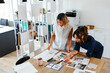 © Westend61 - Colleagues discussing over documents at desk in creative office
