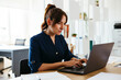 © Westend61 - Businesswoman working on laptop at desk in creative office