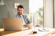 © Westend61 - Smiling businessman working on laptop at desk