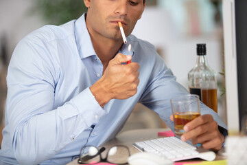 businessman lighting cigaretteand holding alcoholic drink