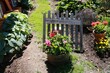 © Richard Redman/Wirestock Creators - Garden with colorful flowers and an aged wooden fence with love laugh live writings carved on it