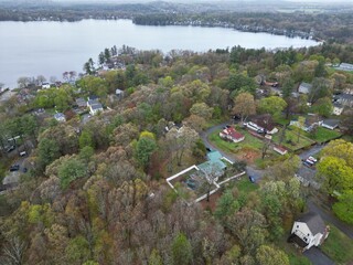 Sticker - Aerial view of lake Attitash and a town near a shoreline surrounded by colorful trees in autumn