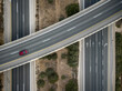 A top down view from a drone of a red car driving on an interchange 