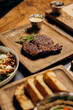 Fresh juicy delicious beef steak on wooden background in restaurant. Meat dish with spices and herbs