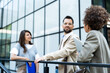 © Srdjan - Business people partners colleagues team and staff member last meeting and discussion before summer vacation break. Businessman with two expert businesswomen strategy talk outside office building