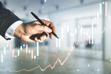 Wall Mural - Man hand with pen working with abstract virtual financial graph on blurred office background, financial and trading concept. Multiexposure