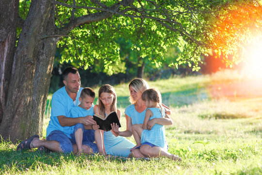 family reading bible in nature