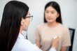 © tong2530 - Asian female doctor using stethoscope to check patient's heartbeat at hospital. Medical and Health Care Concept. selective focus of stethoscope.