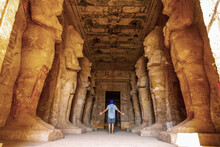 A Young Tourist Looking At The Pharaohs At The Abu Simbel Temple In Southern Egypt In Nubia Along Lake Nasser. Temple Of Pharaoh Ramses II, Travel Lifestyle
