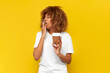 © Богдан Маліцький - young sleepy curly american girl holding paper glass of coffee and yawning on yellow isolated background
